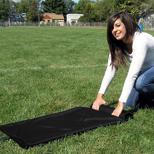 Woman kneeling on grass rolling up a black ultimate sportswrap